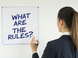 Business person writing What Are The Rules on a whiteboard