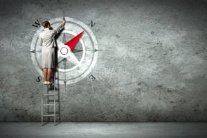 Businesswoman drawing compass with finger on wall standing on ladder