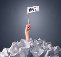 Help flag held up by hand emerging from a pile of papers