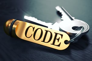 Keys and Golden Keyring with the Word Code over Black Wooden Table with Blur Effect.