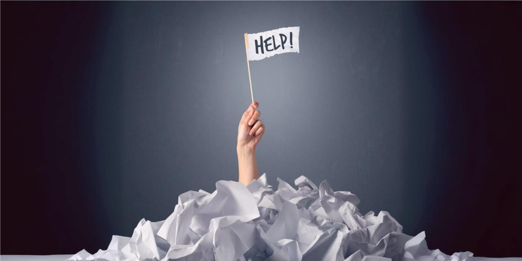 Female hand emerging from crumpled paper pile holding a white flag with help written on it